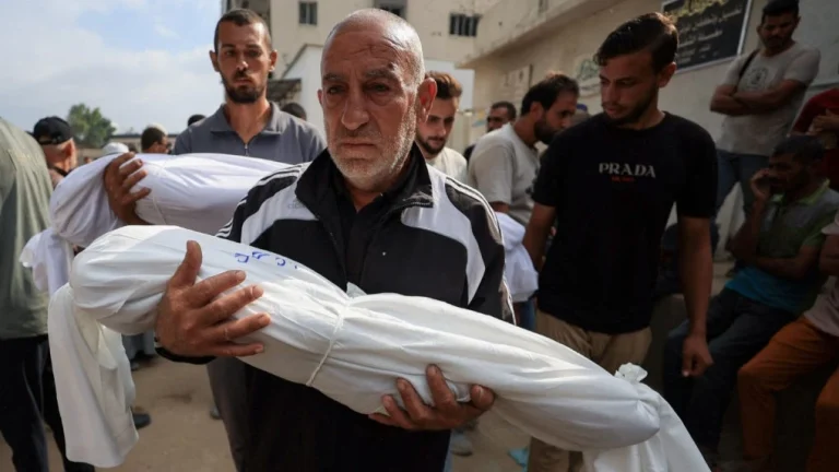 A man carries the body of a child killed by the Israeli army at a funeral in Gaza City. Photo: Dawoud Abu Alkas/Reuters.