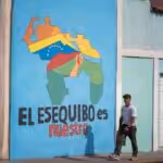 A passerby walks past a mural with a map of Venezuela that says 'The Essequibo is ours," in Caracas. Photo: El Periodico/file photo.