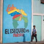 A passerby walks past a mural with a map of Venezuela that says 'The Essequibo is ours," in Caracas. Photo: El Periodico/file photo.