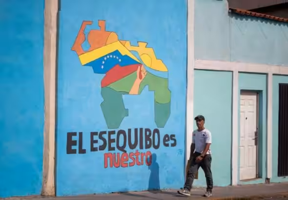 A passerby walks past a mural with a map of Venezuela that says 'The Essequibo is ours," in Caracas. Photo: El Periodico/file photo.