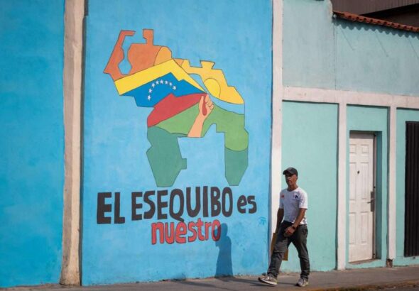 A passerby walks past a mural with a map of Venezuela that says 'The Essequibo is ours," in Caracas. Photo: El Periodico/file photo.