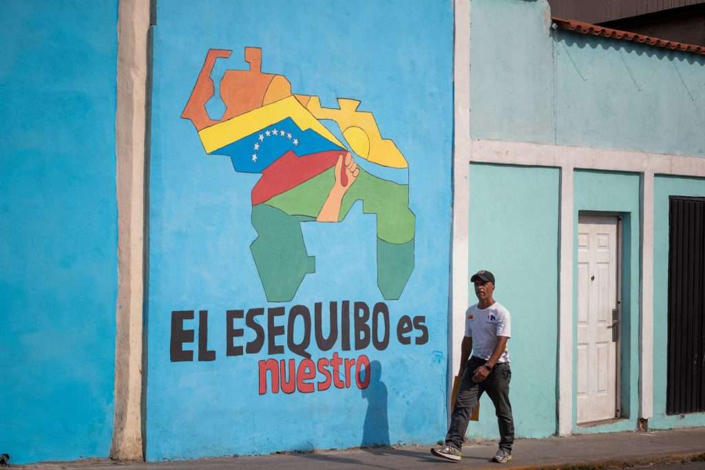 A passerby walks past a mural with a map of Venezuela that says 'The Essequibo is ours," in Caracas. Photo: El Periodico/file photo.