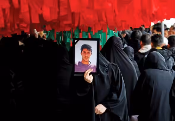 An Iranian woman holds the photograph of a youth killed by US-backed rioters. Photo: Tehran Times.