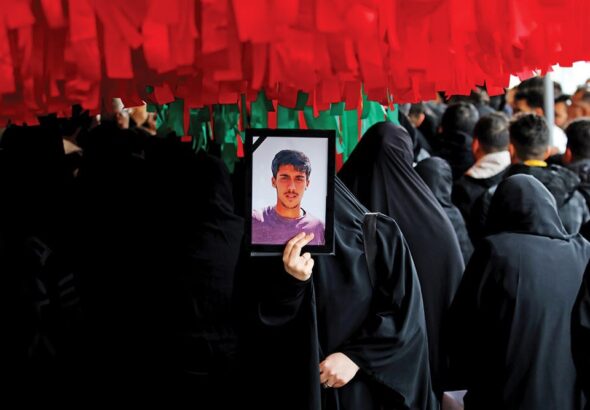 An Iranian woman holds the photograph of a youth killed by US-backed rioters. Photo: Tehran Times.