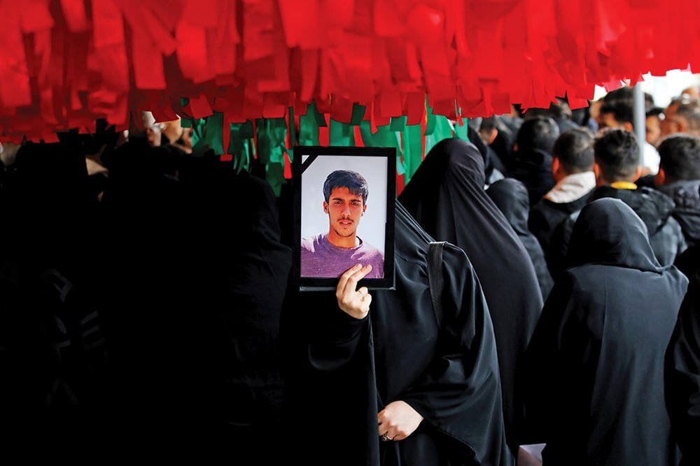 An Iranian woman holds the photograph of a youth killed by US-backed rioters. Photo: Tehran Times.
