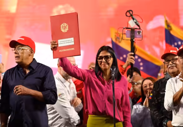 Acting President Delcy Rodriguez holds up the document of the partial reform of the Organic Hydrocarbons Law (LOH) in front of a crowd. Photo: Maxwell Briceno/Reuters.