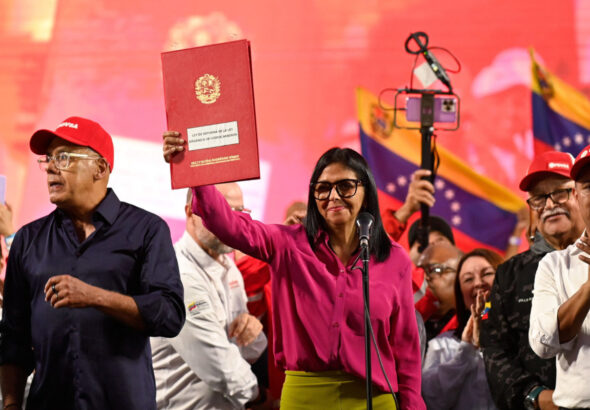 Acting President Delcy Rodriguez holds up the document of the partial reform of the Organic Hydrocarbons Law (LOH) in front of a crowd. Photo: Maxwell Briceno/Reuters.