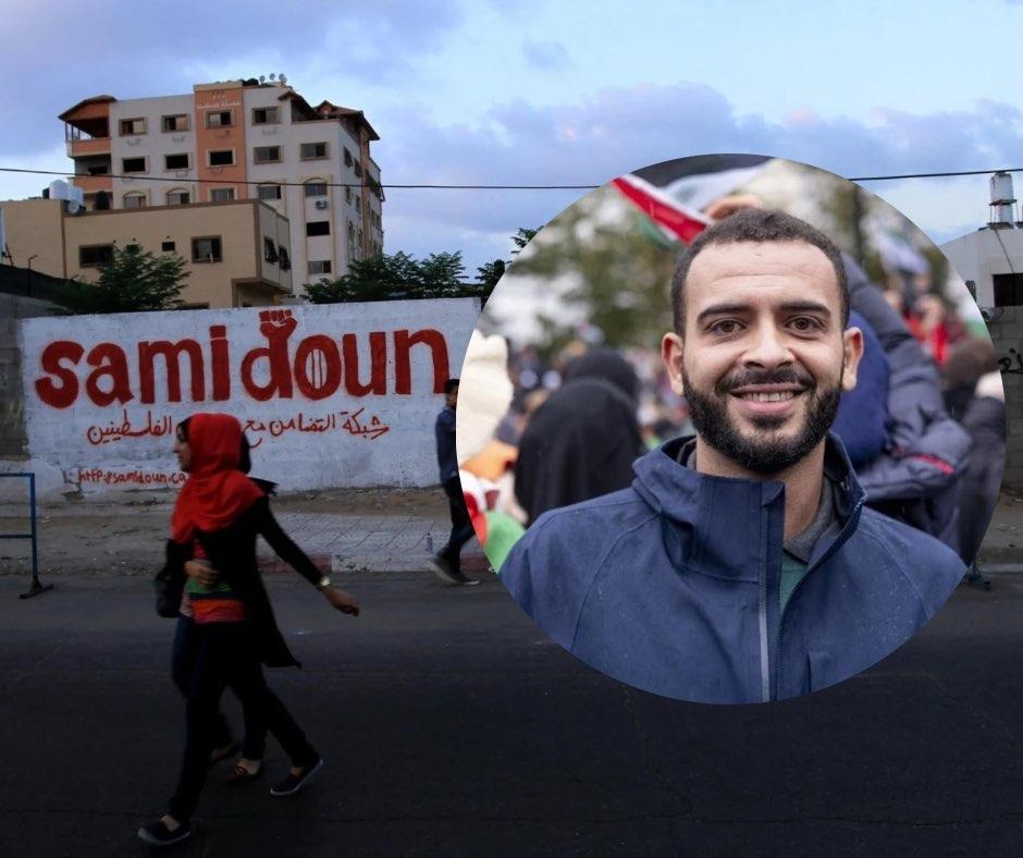 Photo composition: in the foreground Mohammed Khatib and in the background the wall painted with graffiti that says Samidoun. Photo: Samidoun Network.