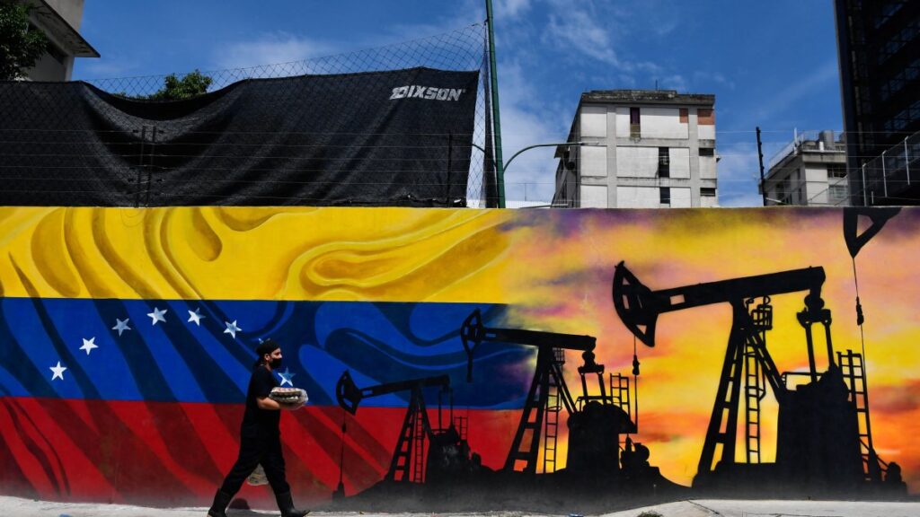 A man wearing a face mask walks past a mural depicting an oil pump and the Venezuelan flag in a street of Caracas, on May 26, 2022. Photo: Federico Parra/AFP/file photo.