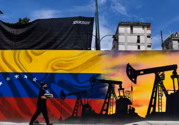 A man wearing a face mask walks past a mural depicting an oil pump and the Venezuelan flag in a street of Caracas, on May 26, 2022. Photo: Federico Parra/AFP/file photo.