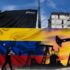 A man wearing a face mask walks past a mural depicting an oil pump and the Venezuelan flag in a street of Caracas, on May 26, 2022. Photo: Federico Parra/AFP/File photo.