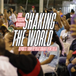 Venezuelan commune members with their arms raised at a meeting. Photo: Monthly Review.