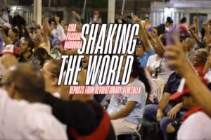 Venezuelan commune members with their arms raised at a meeting. Photo: Monthly Review.
