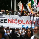 Marchers in Plaza Bolívar, Caracas, Venezuela, hold a banner demanding freedom for President Nicolás Maduro and First Lady Cilia Flores from US imprisonment. Photo: Telesur.