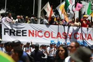 Marchers in Plaza Bolívar, Caracas, Venezuela, hold a banner demanding freedom for President Nicolás Maduro and First Lady Cilia Flores from US imprisonment. Photo: Telesur.