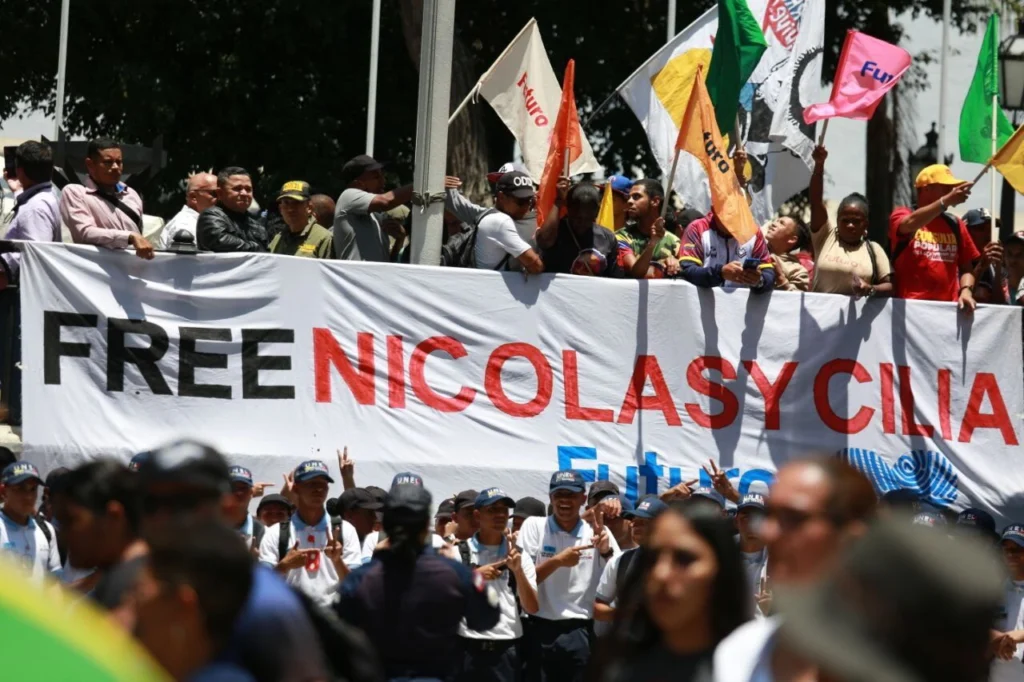 Marchers in Plaza Bolívar, Caracas, Venezuela, hold a banner demanding freedom for President Nicolás Maduro and First Lady Cilia Flores from US imprisonment. Photo: Telesur.