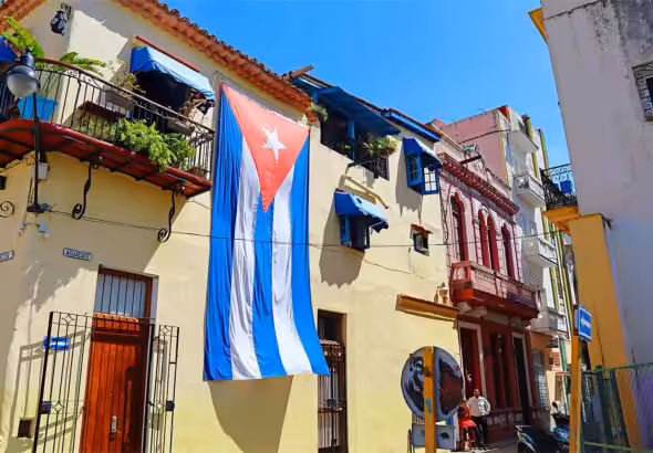 A typical street scene in Old Havana, Cuba, featuring distinctive colonial architecture and a large Cuban flag displayed on a building. Photo: Cigar Aficionado/file photo.