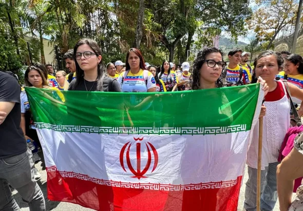 Marchers hold the flag of Iran as they proceed through Caracas, repudiating the US-Zionist aggression on Iran. Photo: José Negrón Valera/Sputnik.