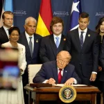 Argentinian President Javier Milei standing behind US President Donald Trump who signs the declaration of the Shield of the Americas summit in Miami. Photo: X/@JMilei.