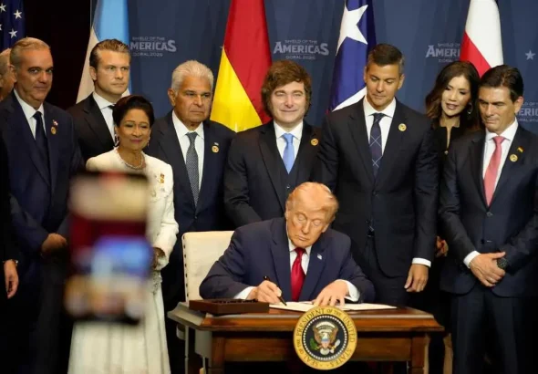 Argentinian President Javier Milei standing behind US President Donald Trump who signs the declaration of the Shield of the Americas summit in Miami. Photo: X/@JMilei.