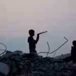 Displaced Palestinian children stand amid the rubble of buildings destroyed during the Israeli bombing of Gaza, at dusk over the Bureij refugee camp in the central Gaza Strip, on November 10, 2025. Photo: Eyad Baba/AFP.