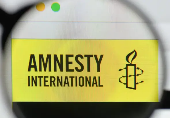 An Amnesty International logo seen through a magnifier. Photo: Casimiro/Alamy/file photo.