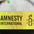 An Amnesty International logo seen through a magnifier. Photo: Casimiro/Alamy/file photo.