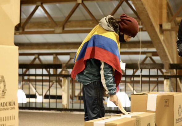 A Colombian voter, wearing a poncho with the colors of the Colombian flag, casts his ballot. File photo.