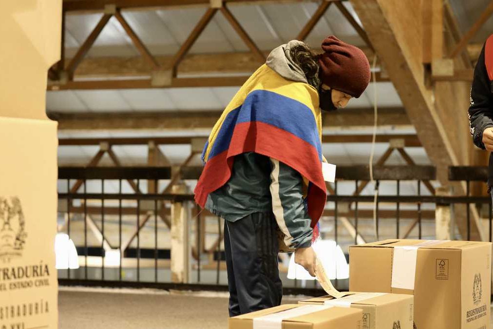 A Colombian voter, wearing a poncho with the colors of the Colombian flag, casts his ballot. File photo.