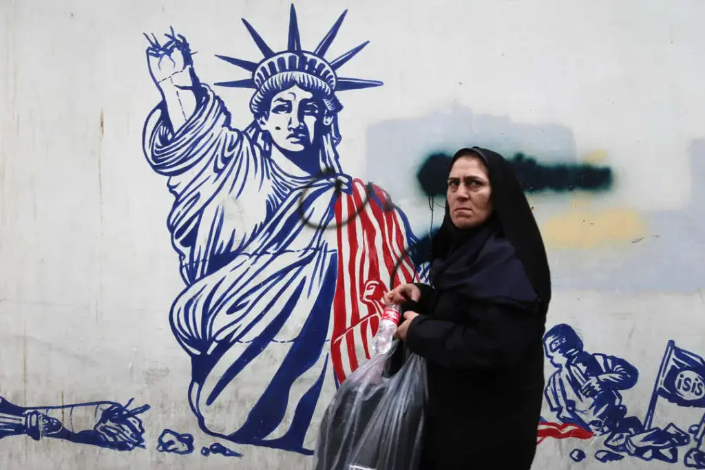 An Iranian woman poses in front of a mural painted on the wall of the former US embassy in Tehran. Photo: Rouzbeh Fouladi.