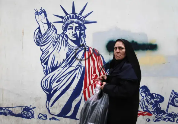 An Iranian woman poses in front of a mural painted on the wall of the former US embassy in Tehran. Photo: Rouzbeh Fouladi.