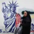 An Iranian woman poses in front of a mural painted on the wall of the former US embassy in Tehran. Photo: Rouzbeh Fouladi.