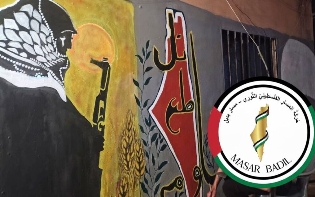 Illustration showing a Palestinian holding a gun in the backdrop of a wall painted with the map of Palestine, an olive branch, and wheat kernels. Illustration: Masar Badil.