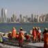 The photo shows construction workers in orange jumpsuits and safety gear working on a coastal project in the United Arab Emirates. Photo: Kamran Jebreili/AP.