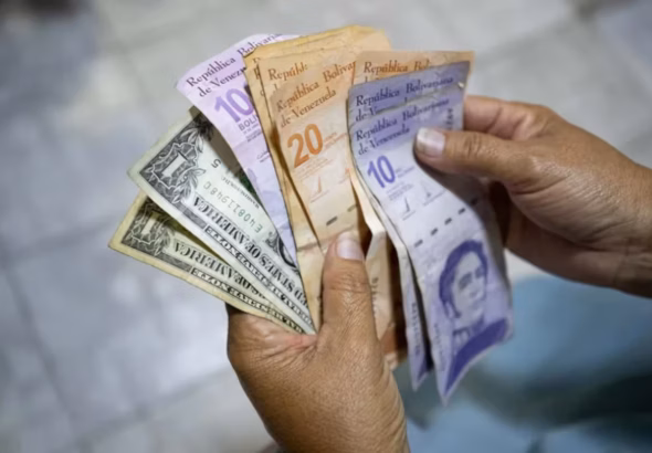 A person holds bolívar and dollar bills. File photo.