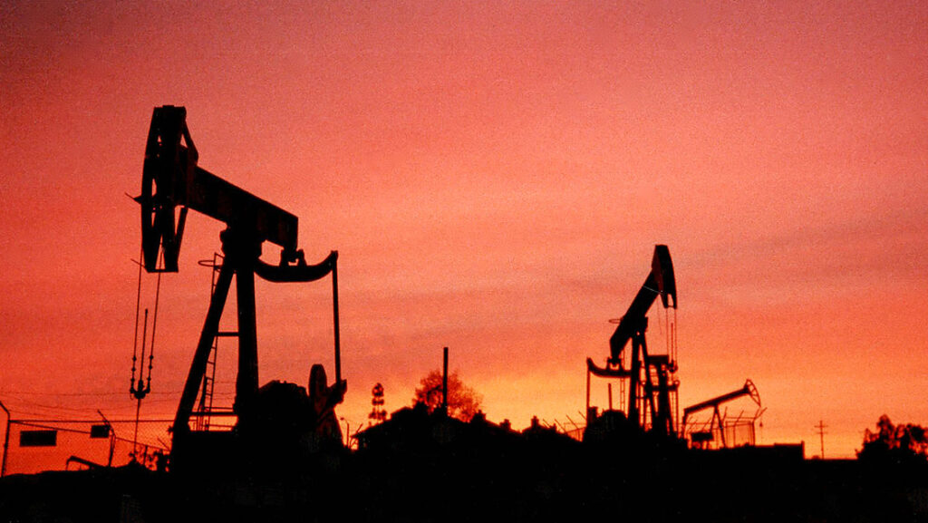 Silhouette of oil rigs against a sunset sky. Photo: Bob Riha, Jr./Getty Images.