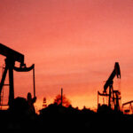 Silhouette of oil rigs against a sunset sky. Photo: Bob Riha, Jr./Getty Images.