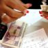 A person counts Cuban banknotes at a table containing receipts and a calculator. File photo.