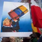 A protester holds a sign with a caricature of Donald Trump drinking Venezuelan oil. Photo: David Canales/Zuma Press/ContactoPhoto.