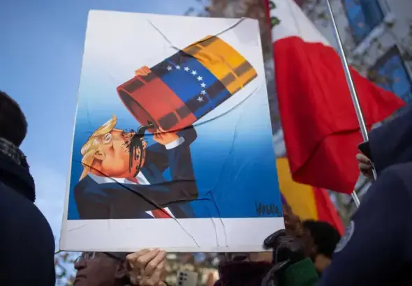 A protester holds a sign with a caricature of Donald Trump drinking Venezuelan oil. Photo: David Canales/Zuma Press/ContactoPhoto.