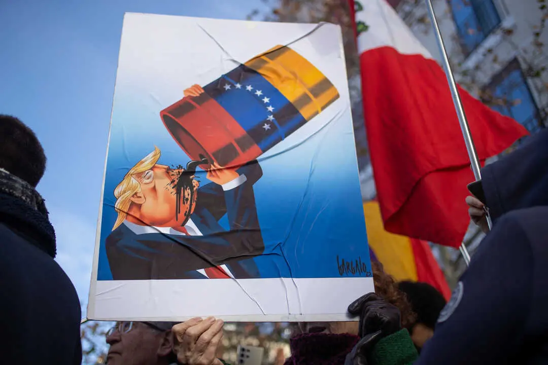 A protester holds a sign with a caricature of Donald Trump drinking Venezuelan oil. Photo: David Canales/Zuma Press/ContactoPhoto.
