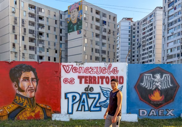 Passerbyer walks in front of a banner that reads “Venezuela is a Peace Territory” in Ciudad Tiuna, Venezuela. Photo: Roger D. Harris.