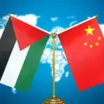 The image shows the flags of Palestine and China displayed together in front of a world map. Photo: Friends of Socialist China.