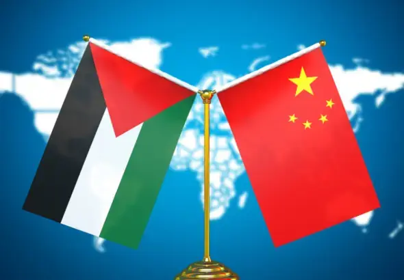 The image shows the flags of Palestine and China displayed together in front of a world map. Photo: Friends of Socialist China.