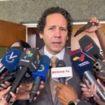 Venezuelan minister for transport, Francisco Garcés, speaking to reporters surrounded by microphones. Photo: File photo.