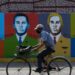 A man rides a bicycle in front of Hugo Chávez graffiti in Barinas on January 7, 2022